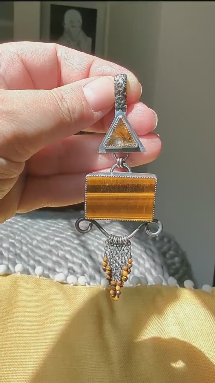 Video of a warm statement pendant with triangular rutile quartz bail and tiger’s eye center